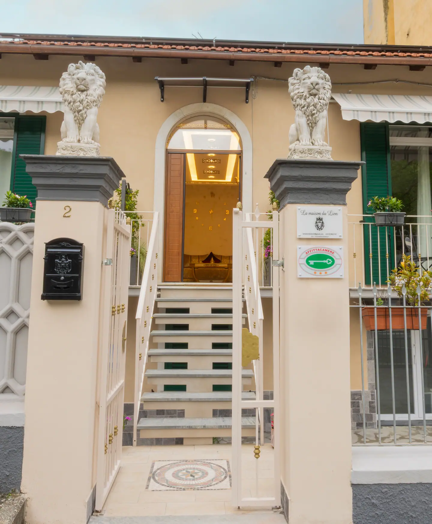 L'ingresso ad arco della villa, fiancheggiato da due leoni di marmo, con il corridoio dorato illuminato all'interno