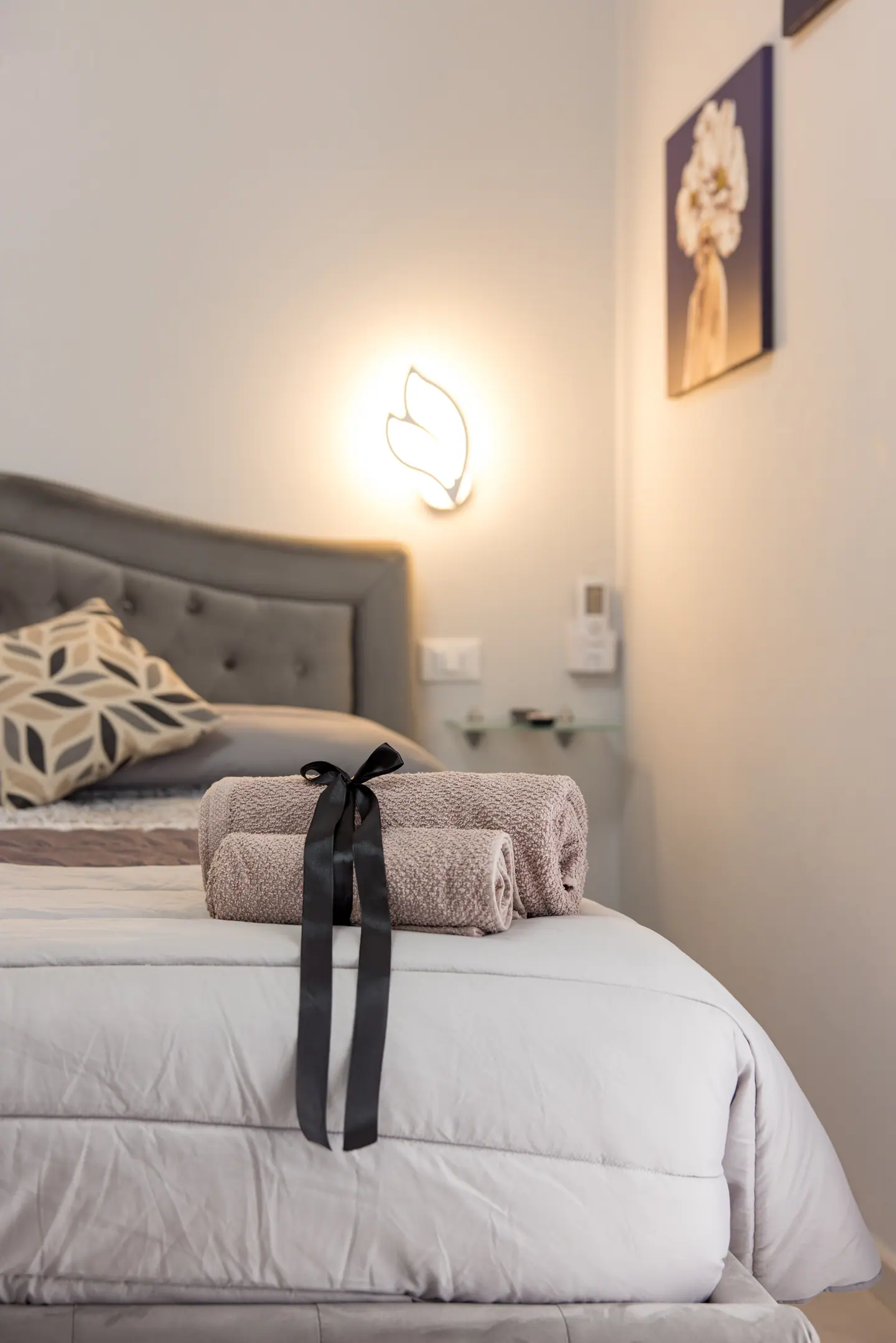 Asciugamano arrotolato sul letto sotto l'applique a foglia