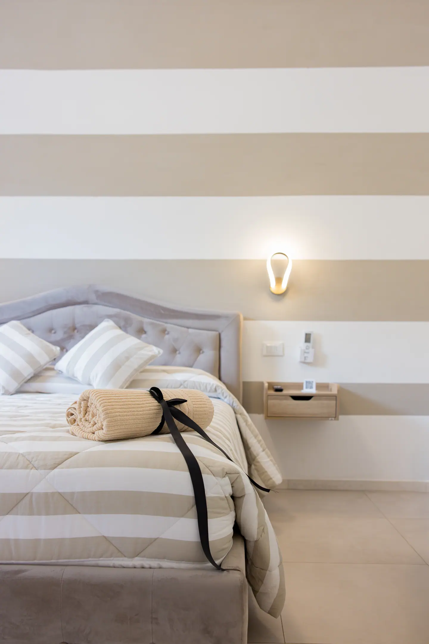 Angolo del letto con righe tortora e applique a goccia